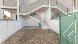 A building with a central staircase, a green gate, and a courtyard with a brick floor. - 2 Bedroom Apartment in Rivabella di Gallipoli RB152 (Rivabella)