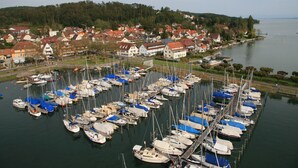 A marina with numerous boats docked, surrounded by residential buildings and a forested hillside. - Apartment "Lindau" with Shared Terrace, Garden, and Wi-Fi (Uhldingen-Mühlhofen)