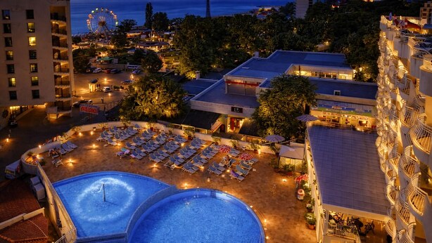 Ein Hotel mit Poolbereich, mehreren Etagen und einem Riesenrad im Hintergrund.