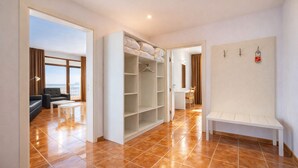 Ein Hotelzimmer mit großem Kleiderschrank, einer Sitzecke mit Sofa und Tisch und Blick durch eine offene Tür.