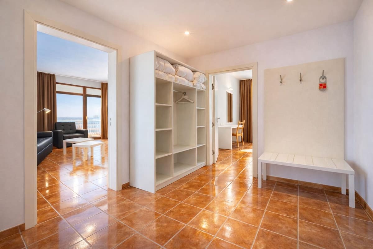 Une chambre d’hôtel dotée d’une grande armoire, d’un coin salon avec un canapé et une table, et offrant une vue sur l’extérieur grâce à une porte ouverte.
