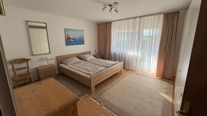 A bedroom with a wooden bed, a nightstand, a dresser, a mirror, and a painting on the wall. - Apartment Hoeri with Private Garden, Terrace, and Wi-Fi (Uhldingen-Mühlhofen)