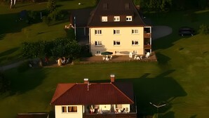 A two-story house with a red roof, a balcony, and a well-maintained lawn. - Apartment Hoeri with Private Garden, Terrace, and Wi-Fi (Uhldingen-Mühlhofen)