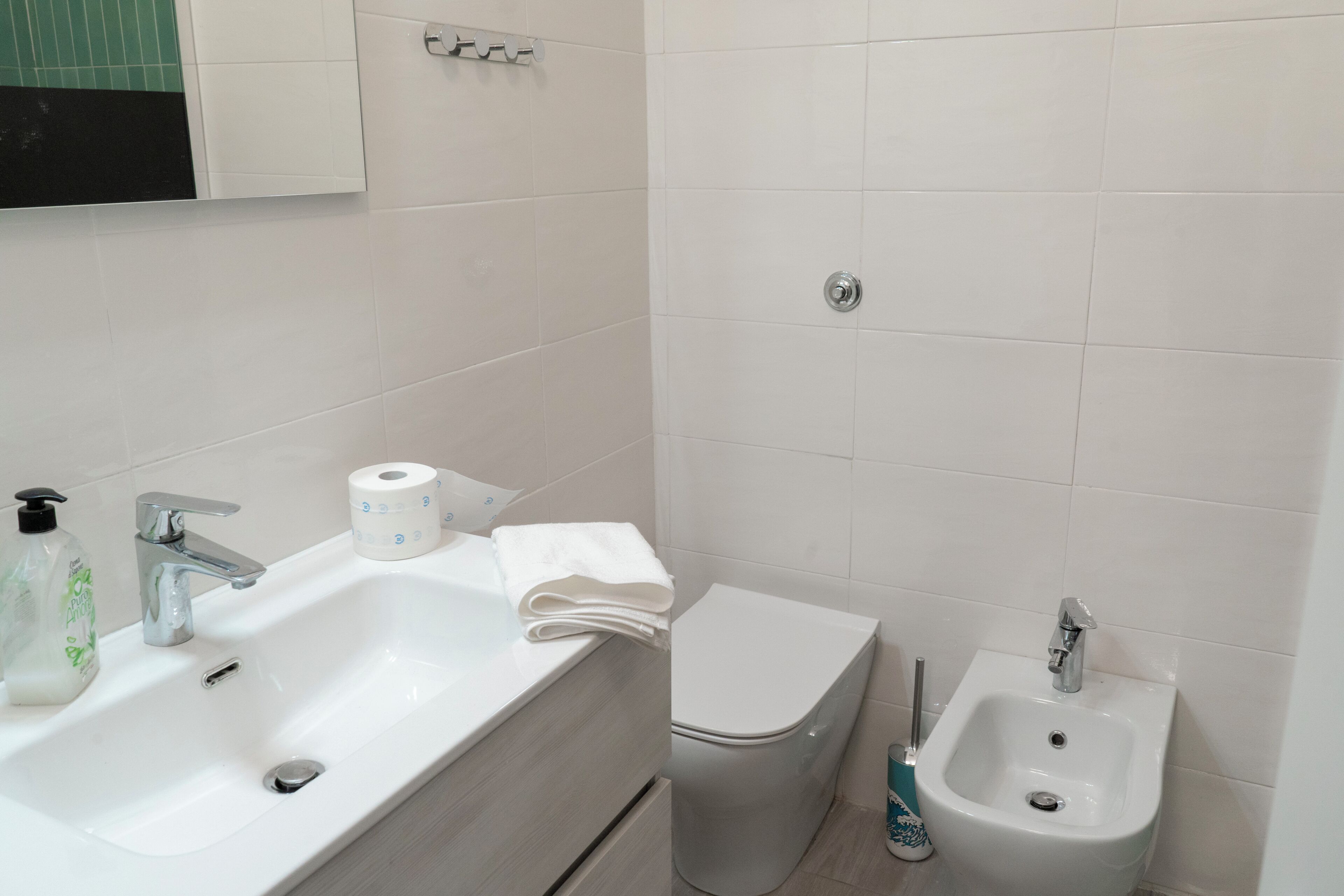Une salle de bain équipée d’un lavabo, d’un bidet, de toilettes et d’un miroir.