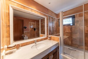 Un bagno moderno con uno specchio grande, un lavandino e una doccia con pareti in vetro.