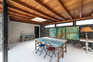 Ein Zimmer mit Holzboden, Steinwand, Tisch und Stühlen sowie einer Lampe.