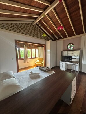A room with a massage table, a desk, a chair, and a window with curtains.