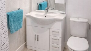 Un bany amb un mànec blanc, un vàter, cortina de bany i una tovallola blava.