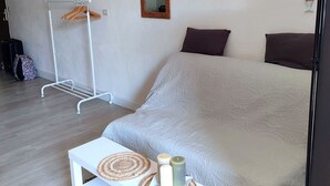 Un dormitori amb un llit, una taula de nit amb espelmes, una làmpada penjant, un penjallot i un mirall.