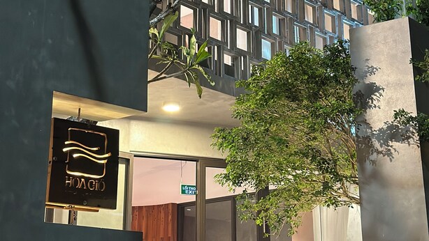 A modern building with a geometric facade, a visible entrance, and a sign that reads 'HOAGIO.' - Hoa Gió Boutique Stay (Hue)