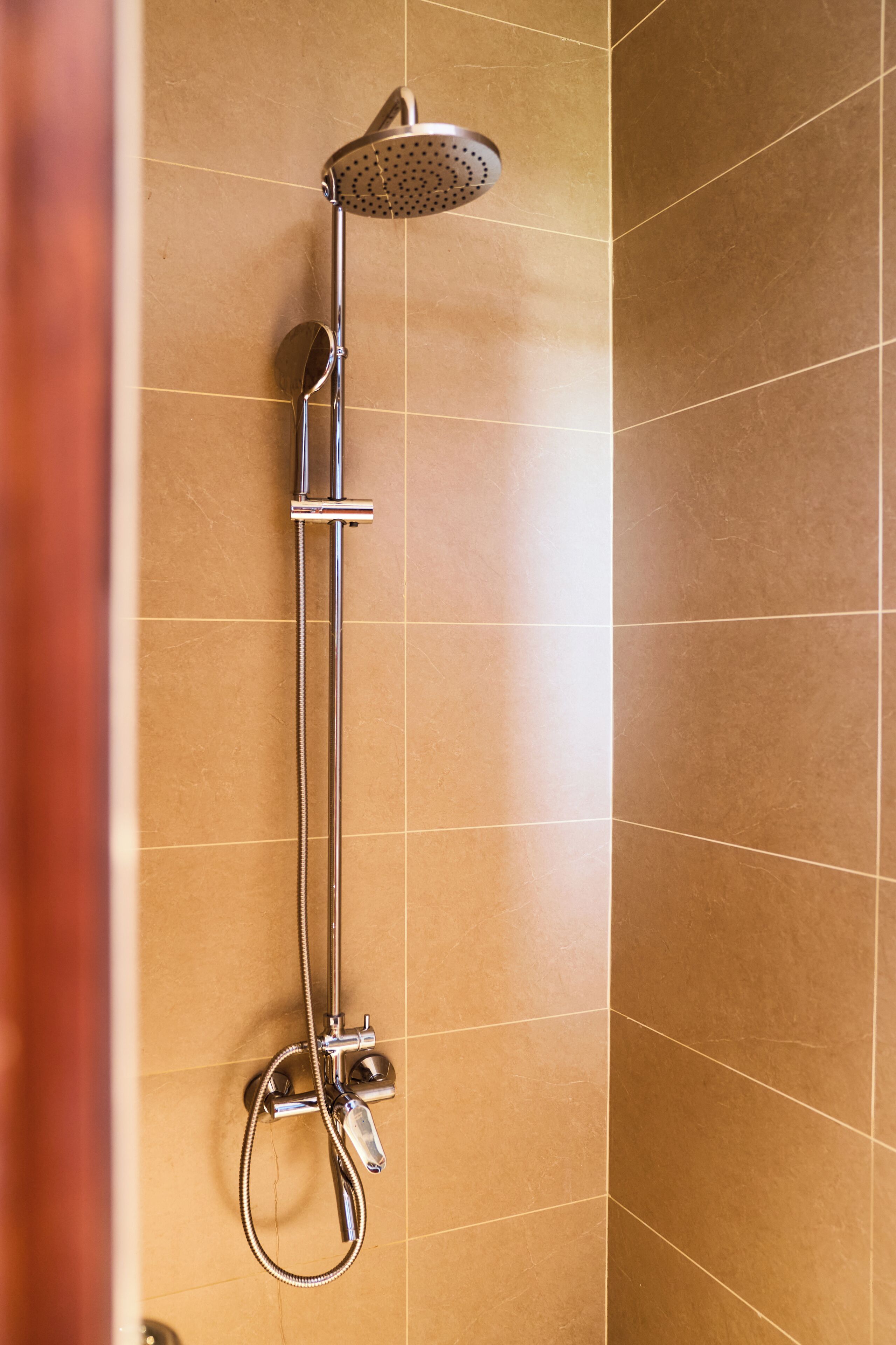 A shower with a handheld showerhead and a wall-mounted faucet.