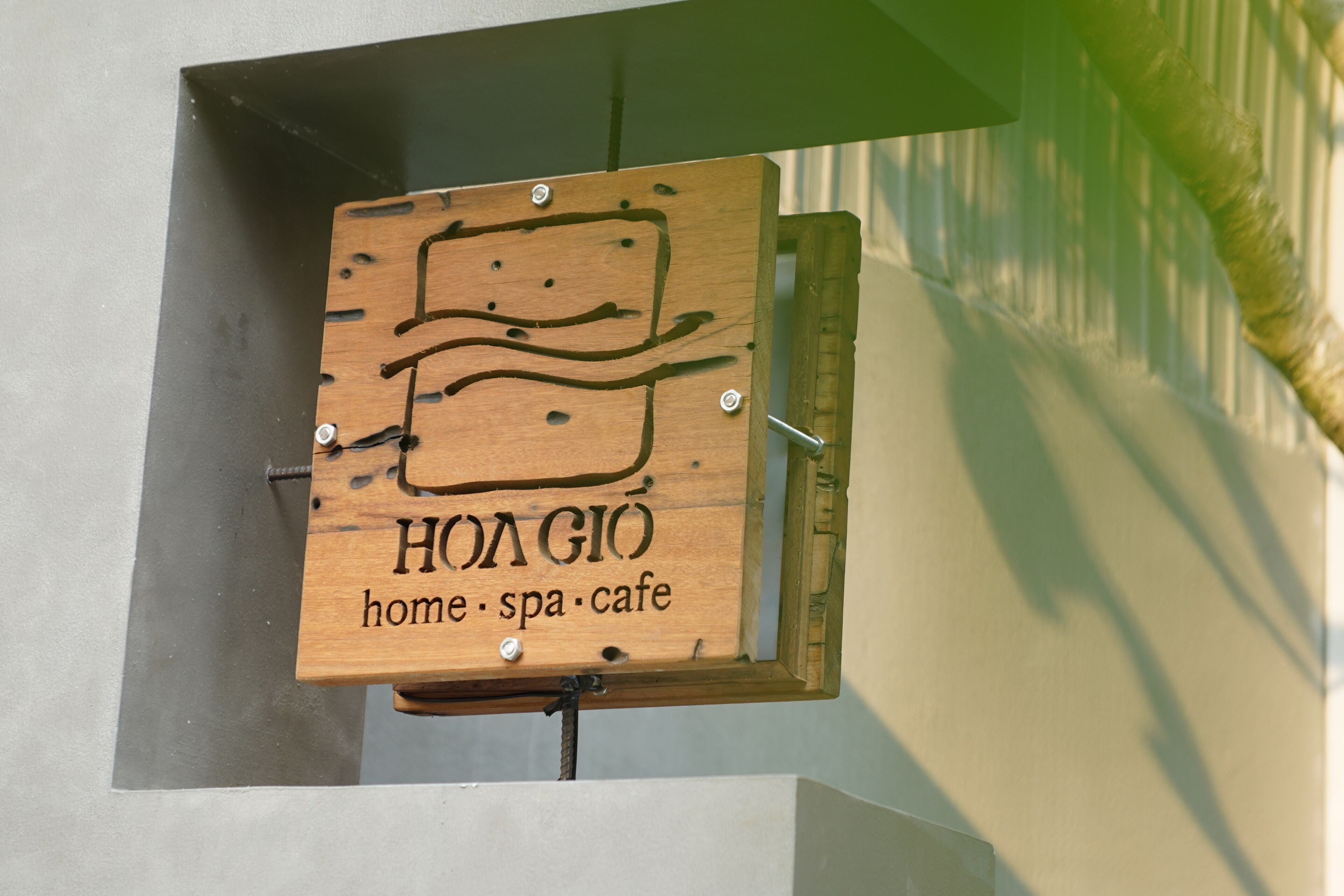 A wooden sign with the text 'HOAGIO home spa cafe' mounted on a metal bracket.