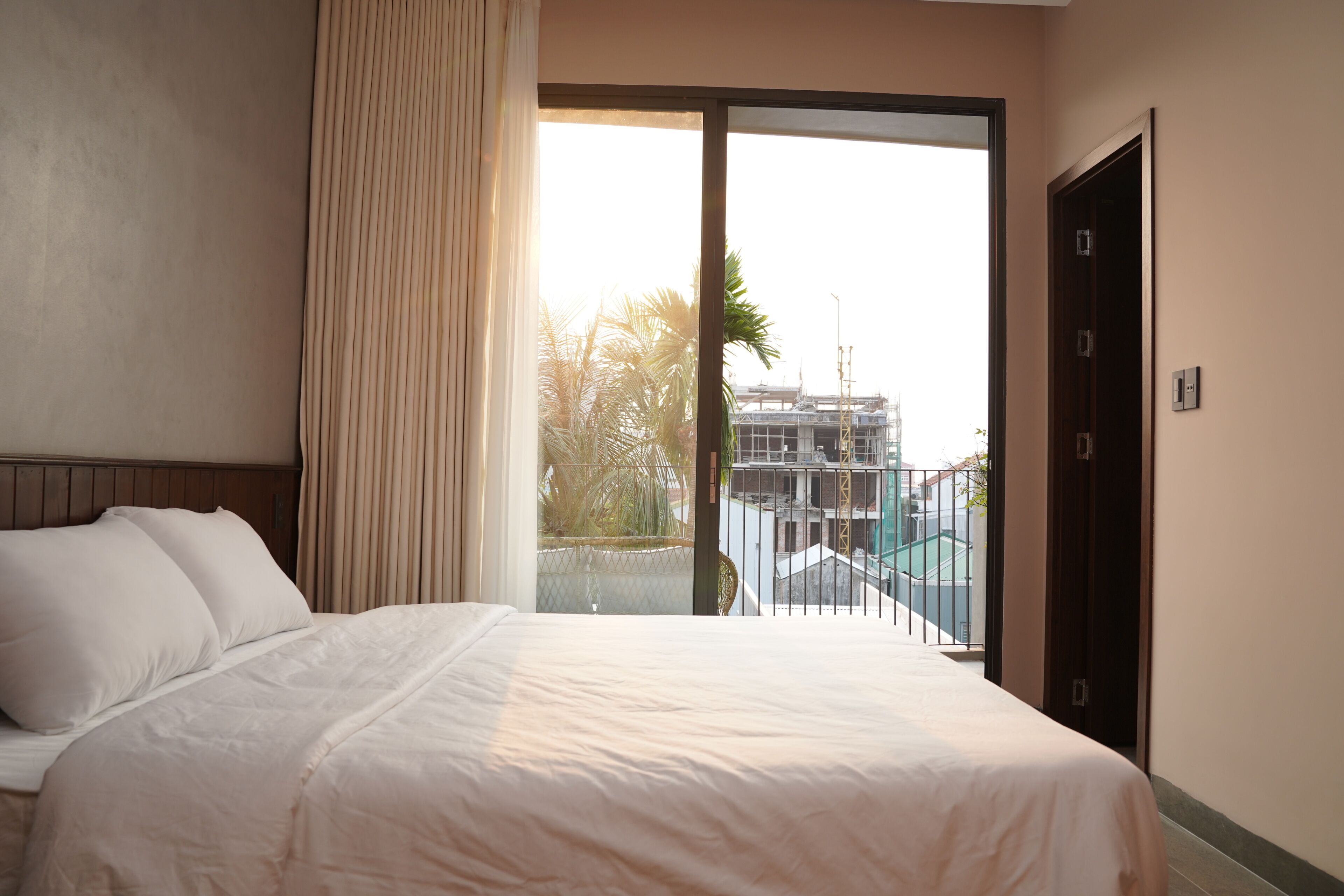 Una camera d'albergo con un letto, una finestra vista edifici e un balcone.