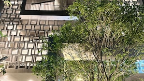 A modern building with a geometric facade, a tree in the foreground, and a glimpse of an interior with a sofa and table. - Hoa Gió Boutique Stay (Hue)
