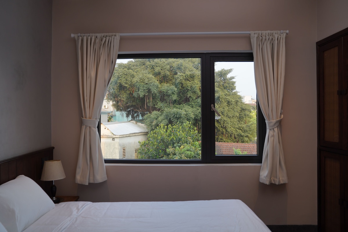 Una camera da letto con un'ampia finestra, un letto, un comodino e una lampada.