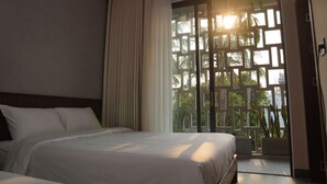 A hotel room with a bed, a large window with a view of greenery, and a sliding door. - Hoa Gió Boutique Stay (Hue)