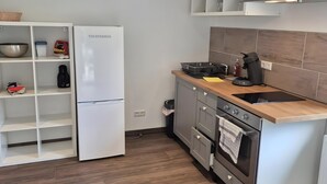 A modern kitchen with a white refrigerator, wooden countertop, stainless steel oven, and a herringbone-patterned floor. - Apartment 'Fewo Am Adlerweiher' with Shared Terrace, Shared Garden and Wi-Fi (Feldberg (Schwarzwald))