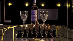 A bar area with a chessboard, two glasses, and a bottle on a reflective surface. - The secret lodge (Dolus-le-Sec)