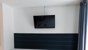 A modern living room with two leather chairs, a small table, a flat-screen TV mounted on the wall, and a black panel below the TV. - Comfort Breakfast Room with Balcony and Moselle View for 2 in Ediger-Eller (20 m²) (Ediger-Eller)