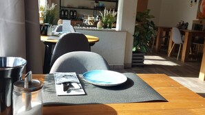 A dining area with a wooden table, chairs, and a menu. - Comfort Breakfast Room with Balcony and Moselle View for 2 in Ediger-Eller (20 m²) (Ediger-Eller)