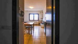 Un couloir menant à une salle à manger avec une fenêtre, un réfrigérateur et une porte.