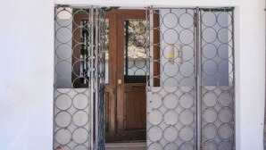 Une entrée d’immeuble avec un portail en métal, une porte en bois et une petite fenêtre située au-dessus de la porte.