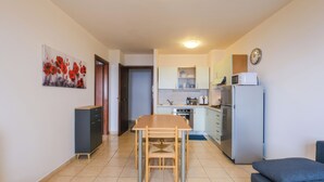 Une cuisine compacte comprenant une table à manger, un four à micro-ondes, un réfrigérateur et une horloge murale.