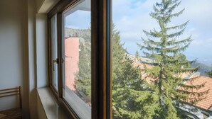 Une fenêtre donnant sur un arbre et des immeubles.
