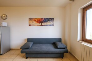 A room with a gray sofa, a wall clock, and a painting of a tree. - Vista Mare (Sarnano)