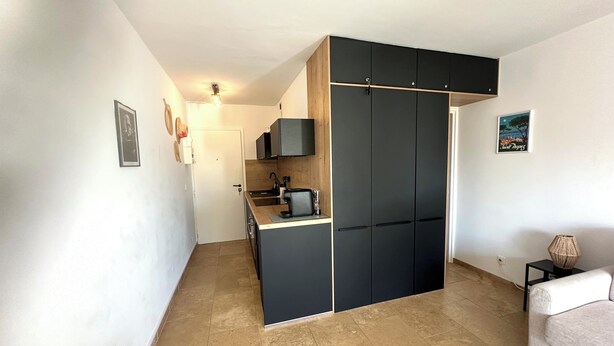 A compact living space with a kitchenette, a sofa, and a small side table. - L'Eden in Downtown Saint-Tropez with a Pool (Saint-Tropez)