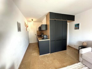 A compact living space with a kitchenette, a sofa, and a small side table. - L'Eden in Downtown Saint-Tropez with a Pool (Saint-Tropez)