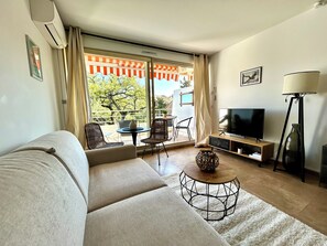 Uma sala de estar com sofá, televisão e um espaço de jantar com cadeiras e mesa.
