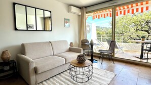 A living room with a sofa, a coffee table, a mirror, and a view of the outdoors. - L'Eden in Downtown Saint-Tropez with a Pool (Saint-Tropez)