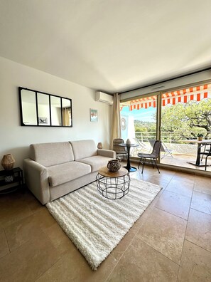 A living room with a sofa, a coffee table, a mirror, and a view of the outdoors. - L'Eden in Downtown Saint-Tropez with a Pool (Saint-Tropez)