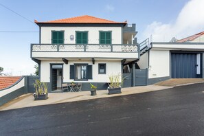 Ein zweistöckiges Haus mit Balkon, Garage und Topfpflanzen im Vorgarten.
