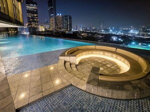 A rooftop pool with a curved seating area and a city skyline in the background. - Luxury 3R2B 5m KLCC Pavilion Embassy 600MBPS Infi (Pavilion Embassy, KLCC, Kuala Lumpur)