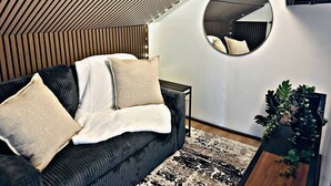 A modern living room with a sofa, pillows, a round mirror, and a potted plant. - Designer Luxe Studio | King Suite + Work Space (Sacramento)