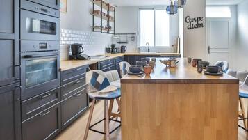 Une cuisine moderne dotée d’appareils électroménagers intégrés, d’un îlot central, de tabourets de bar et d’un panneau décoratif mural.