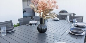 A dining table with a vase of flowers, plates, and cutlery. - La Villa Pop I Talmont I 12 pers I Piscine & Pétanque (Talmont-Saint-Hilaire)