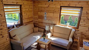 A cozy cabin interior with a sofa, armchair, ottoman, and a small table. - Large, Comfortable Holiday Home With a Garden (Smoldzino)
