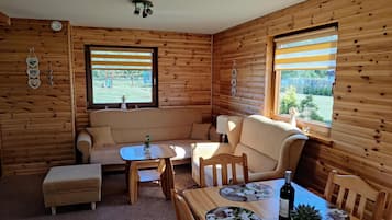 A cozy cabin interior with a sofa, a small table, and a dining area.