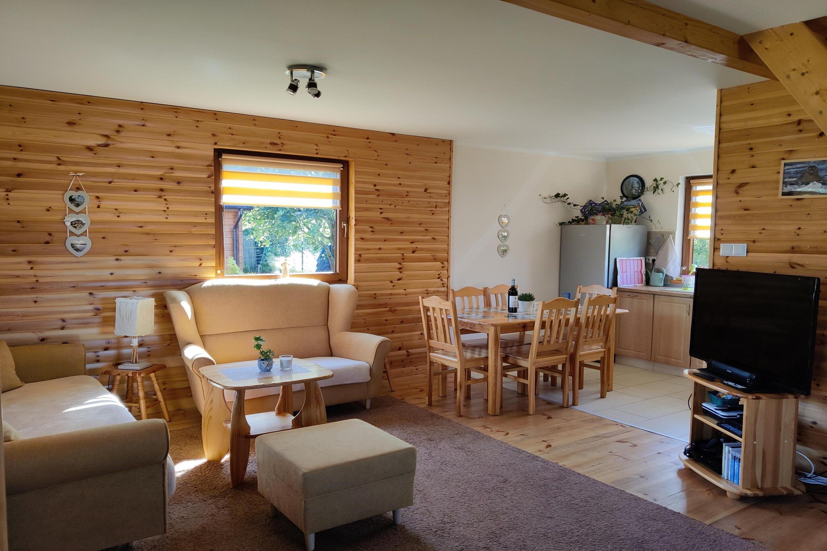 Un intérieur de chalet chaleureux avec un canapé, une table à manger et un meuble pour la télévision.