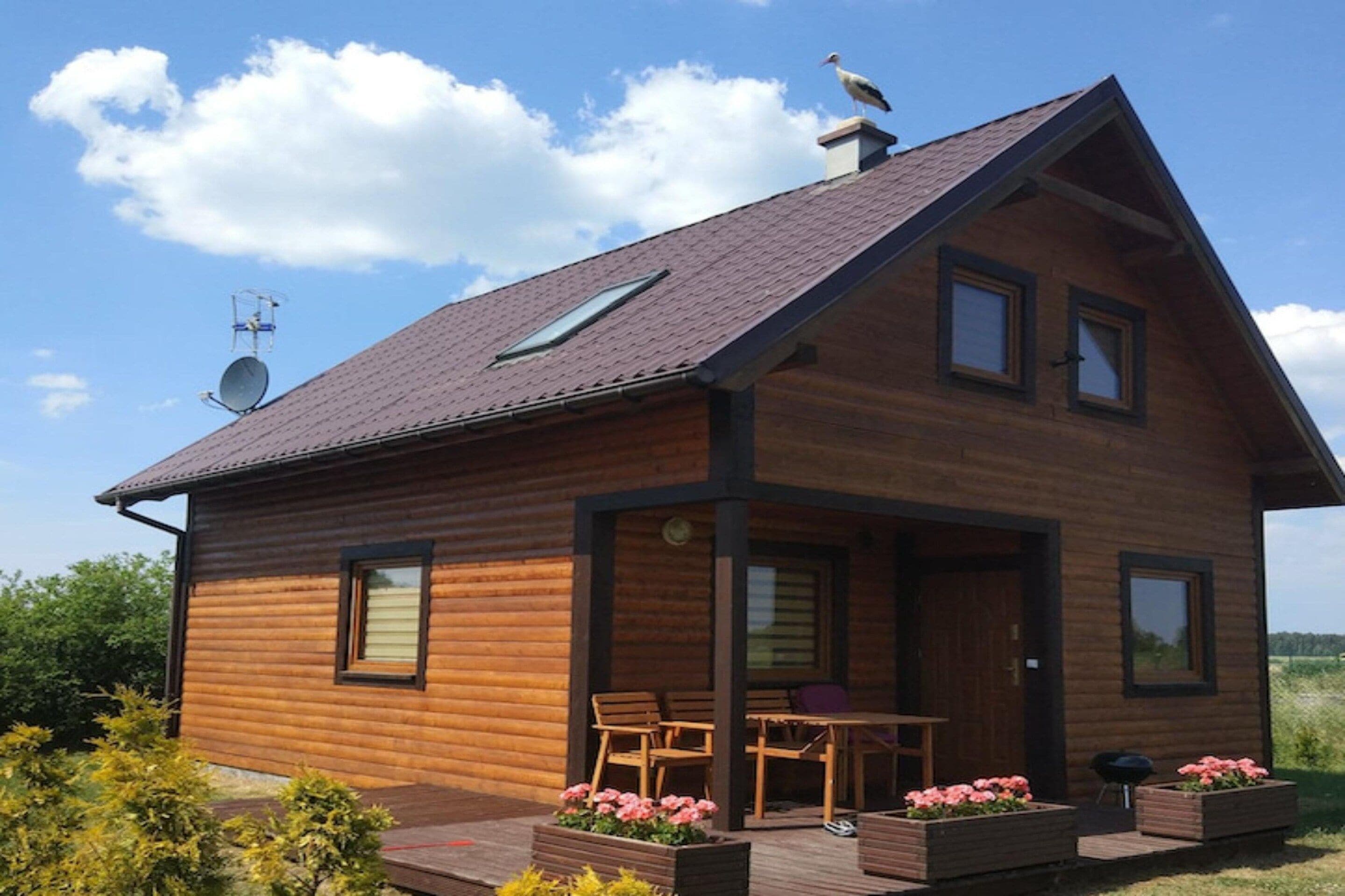 A wooden cabin with a sloped roof, a satellite dish, and a small porch with outdoor seating.