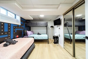A dormitory room with bunk beds, a TV, and a mirror. - Older home in NE Edmonton with a renovated retro interior: hot tub, sauna, Pac-Man & Street Fighter arcade, home theater with projector & popcorn machine. 16 min to downtown, 8 min to Rundle Park golf. Pool closed for the season. Up to 12 guests. (Edmonton)