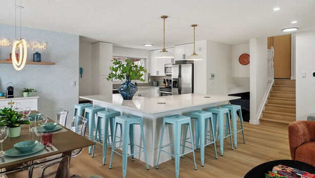 A modern kitchen with a central island, bar stools, and pendant lighting. - Renovated retreat in NE Edmonton with a sauna, Pac-Man & Street Fighter arcade, home theater with projector & popcorn machine. 16 min to downtown, 8 min to Rundle Park golf. Built for families, friend groups & celebrations up to 13 guests. (Edmonton)
