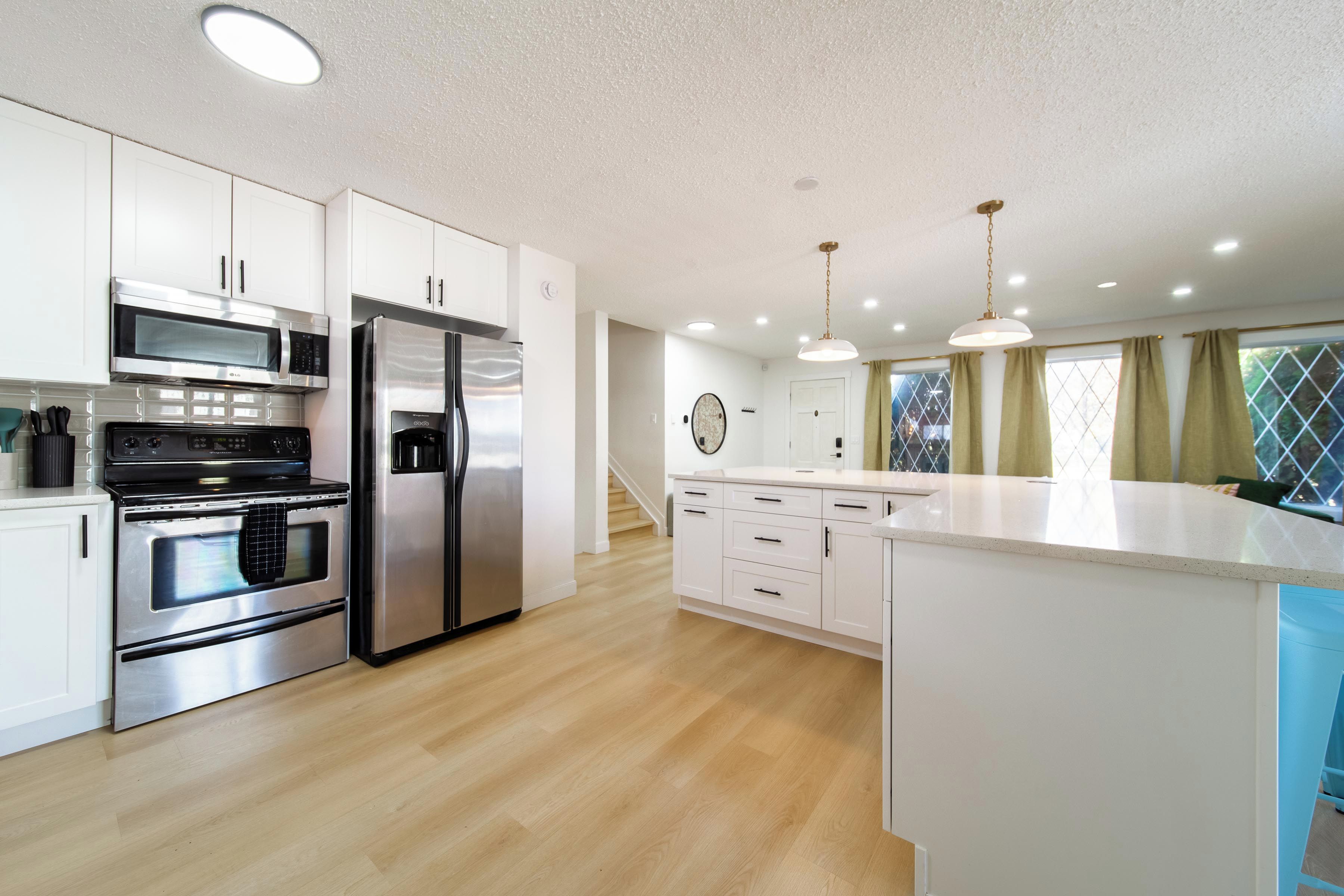 A modern kitchen with stainless steel appliances, white cabinetry, and a central island.