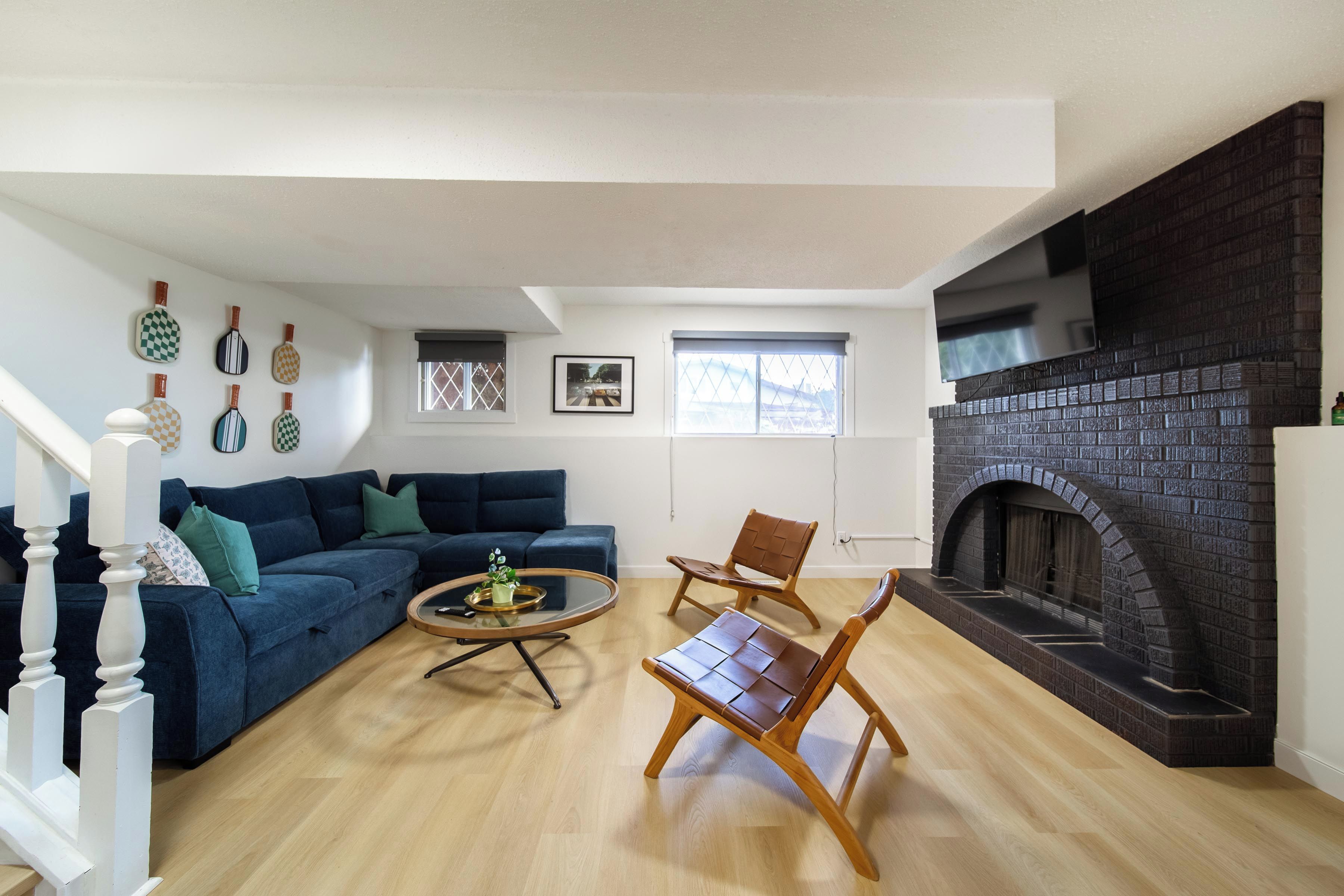 A living room with a dark brick fireplace, a blue sofa, a wooden coffee table, and a wooden chair.