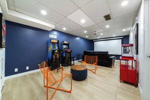 Press start in The Nostalgia Arcade, where Pac Man & Street Fighter cabinets face the projector screen & popcorn machine.