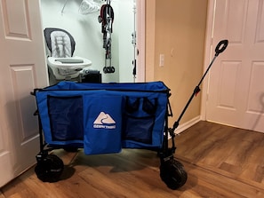 Ein blauer Reisebuggy auf Rädern, ein Kinderwagen und ein Baby-Sitz im Hintergrund.