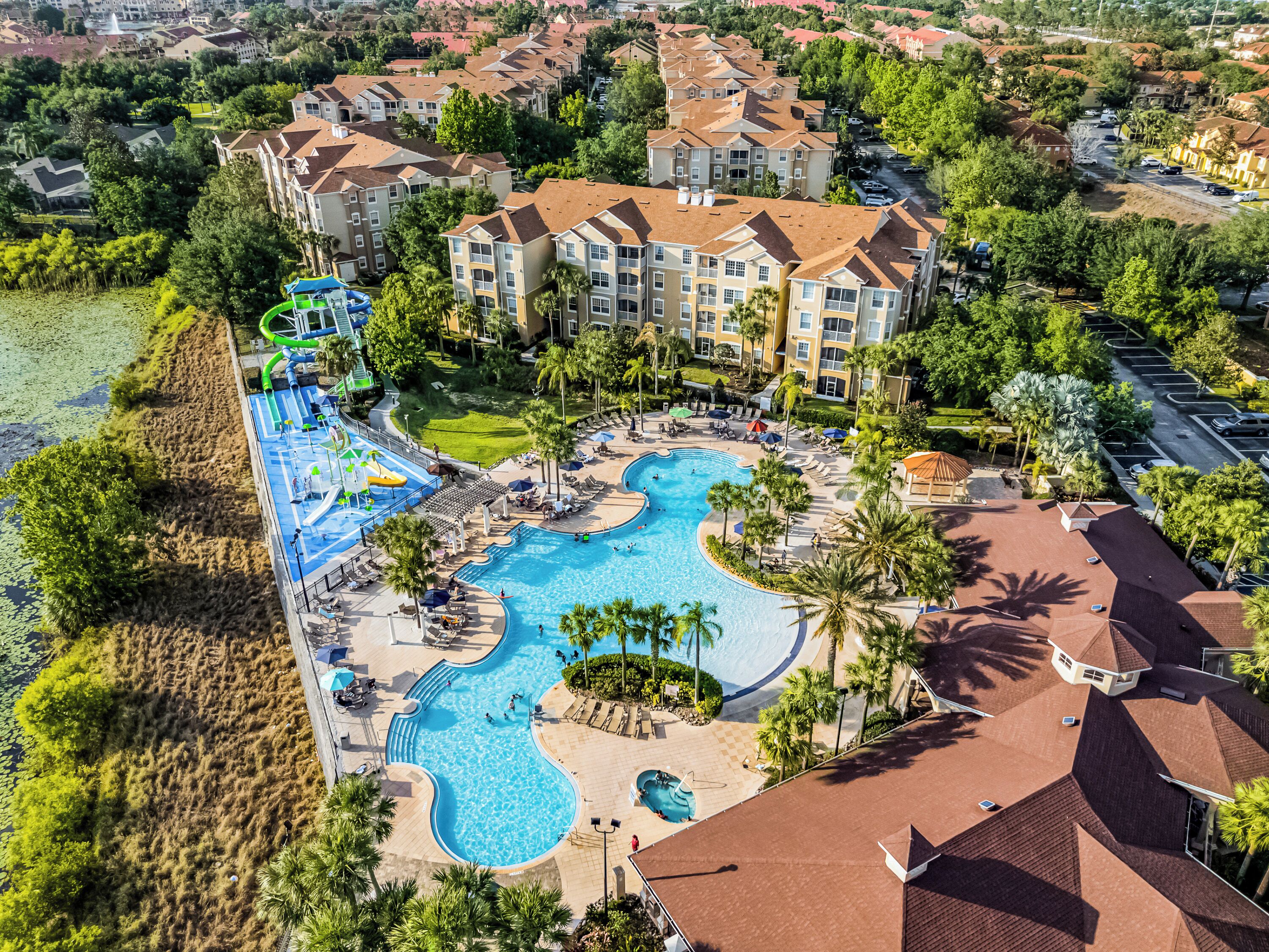 Un resort con una gran piscina, varias zonas de descanso y un parque acuático.